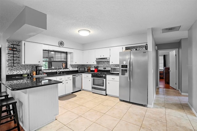 1195 Glen Royal Ter, Deland, FL 32720 - kitchen with stainless steel appliances, under cabinet range hood, a peninsula, light tile patterned flooring, and backsplash
