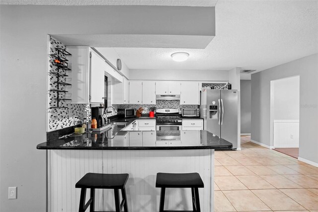1195 Glen Royal Ter, Deland, FL 32720 - kitchen with appliances with stainless steel finishes, a peninsula, a sink, dark countertops, and tasteful backsplash