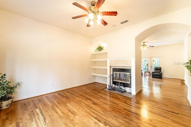 unfurnished living room with french doors, light wood-type flooring, and ceiling fan