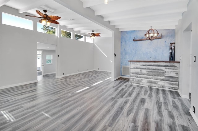 living room with beamed ceiling, ceiling fan with notable chandelier, light wood-type flooring, and a high ceiling