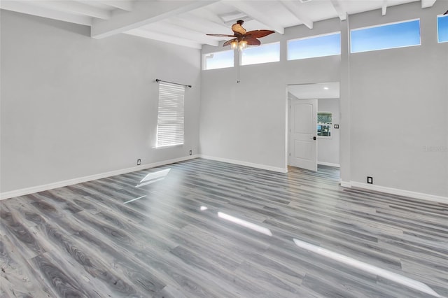 spare room featuring beam ceiling, hardwood / wood-style flooring, and high vaulted ceiling