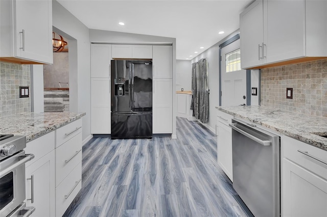 kitchen with white cabinetry, stainless steel appliances, vaulted ceiling, decorative backsplash, and light wood-type flooring