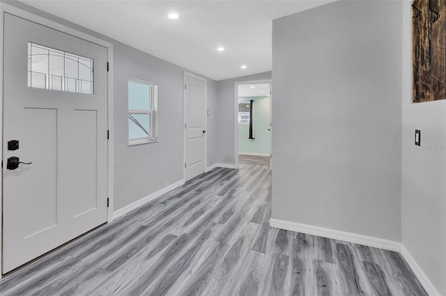 foyer entrance with light wood-type flooring and vaulted ceiling