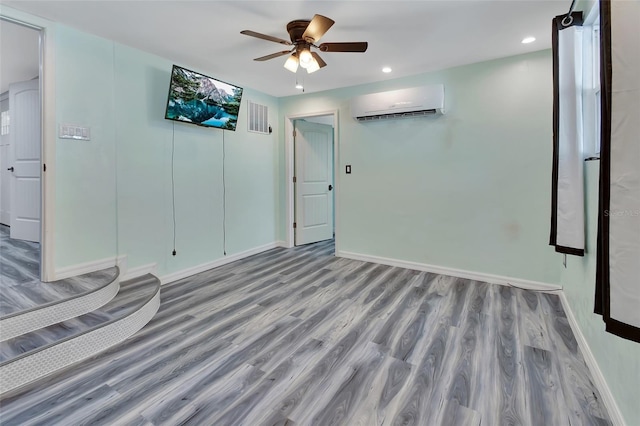 spare room featuring wood-type flooring, a wall mounted AC, and ceiling fan