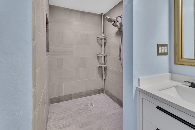 bathroom featuring a tile shower and vanity