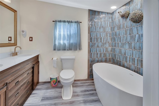 bathroom featuring wood-type flooring, vanity, toilet, and a bathing tub