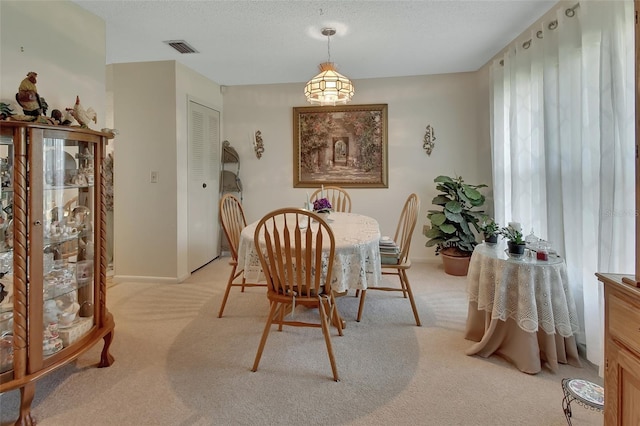 dining room with light carpet and a textured ceiling