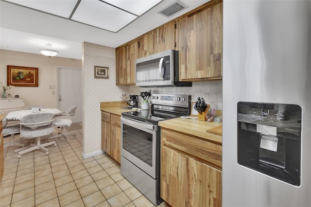 kitchen featuring decorative backsplash, light tile patterned flooring, and stainless steel appliances