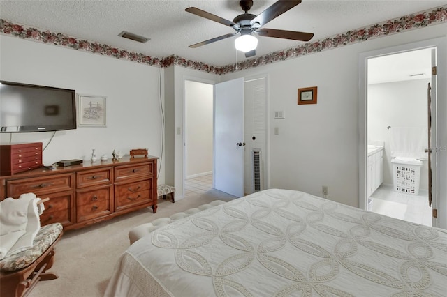 bedroom with ensuite bath, ceiling fan, a textured ceiling, light colored carpet, and a closet