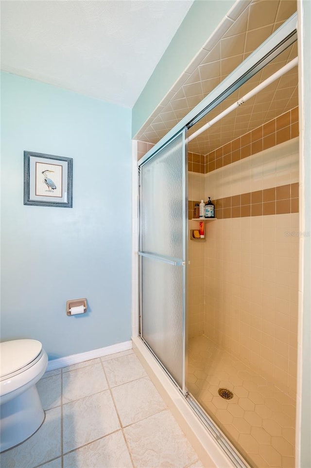 bathroom featuring toilet, tile patterned floors, and a shower with door