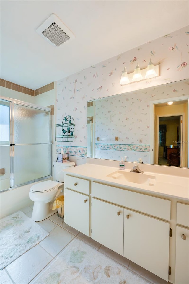 full bathroom with toilet, vanity, tile patterned floors, and bath / shower combo with glass door