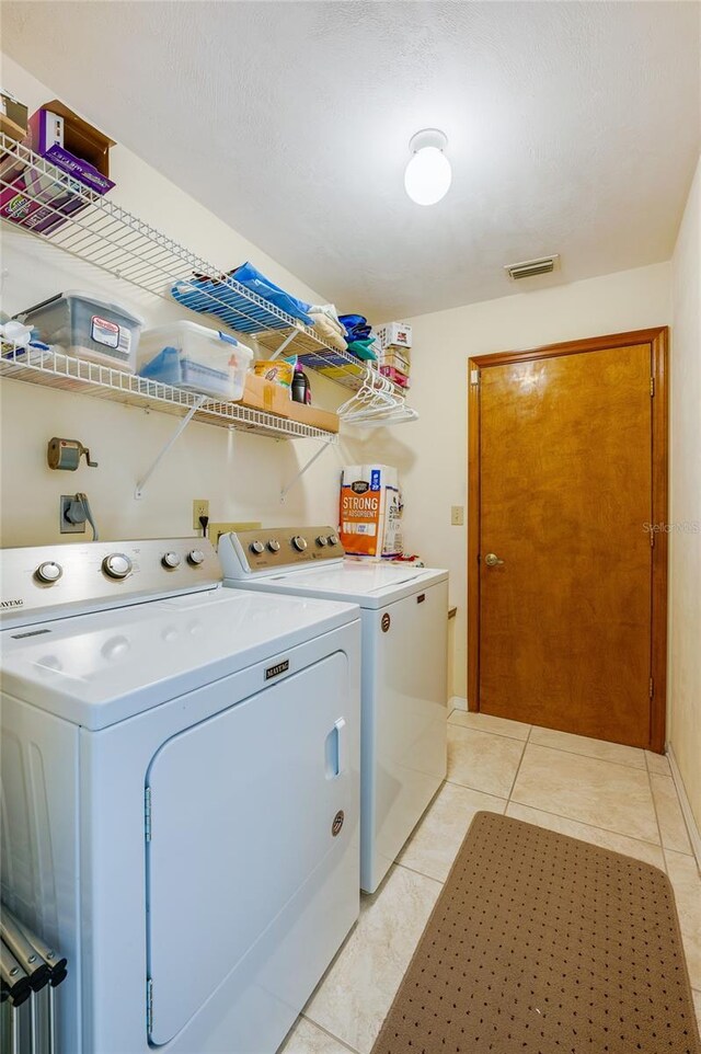 washroom with washing machine and dryer and light tile patterned floors