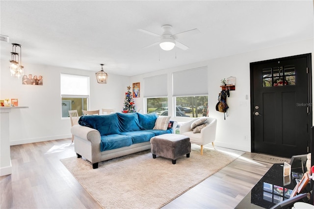 living room with ceiling fan with notable chandelier and light hardwood / wood-style floors