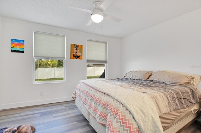 bedroom featuring ceiling fan, wood-type flooring, and a textured ceiling