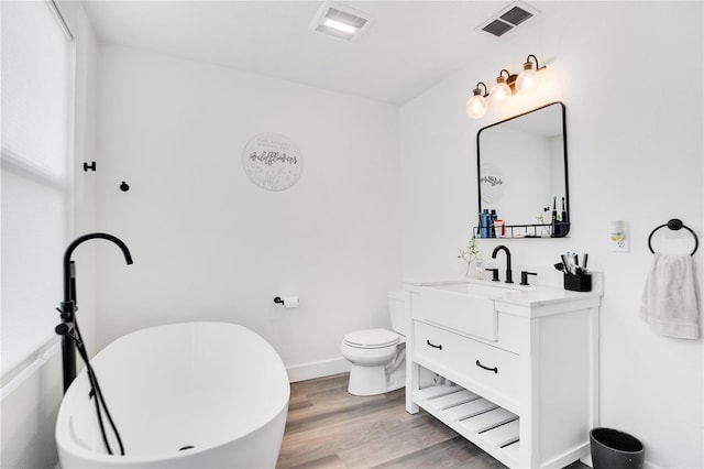 bathroom with vanity, hardwood / wood-style flooring, toilet, and a bathtub