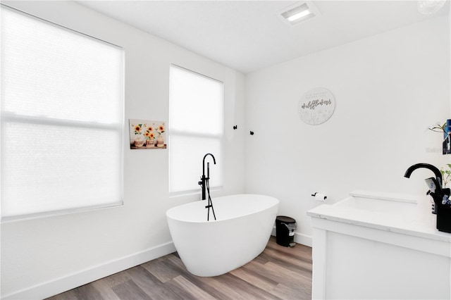 bathroom with hardwood / wood-style floors, a healthy amount of sunlight, and a tub to relax in