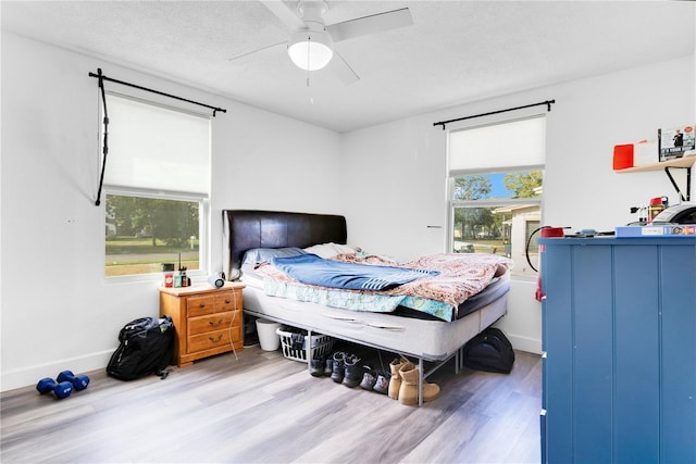 bedroom featuring hardwood / wood-style floors, ceiling fan, a textured ceiling, and multiple windows