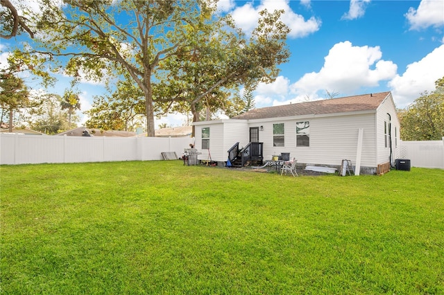 back of property with central air condition unit and a yard