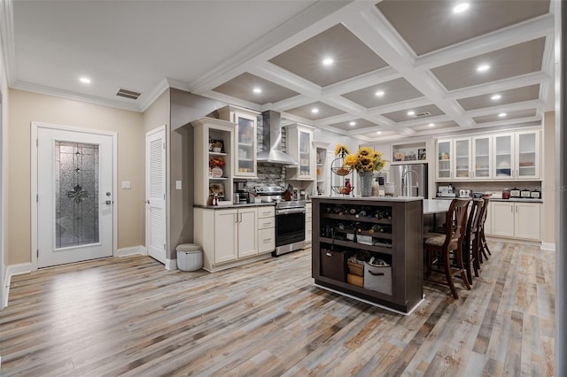 kitchen with open shelves, a breakfast bar area, appliances with stainless steel finishes, wall chimney range hood, and visible vents