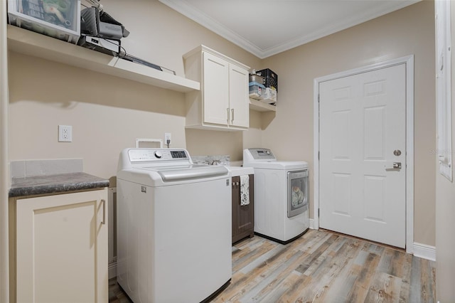 clothes washing area with washer and clothes dryer, crown molding, baseboards, light wood finished floors, and cabinet space