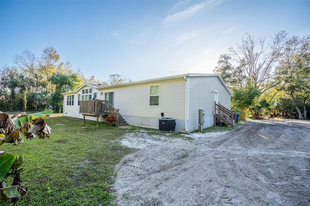 back of property with driveway, central AC unit, and a lawn