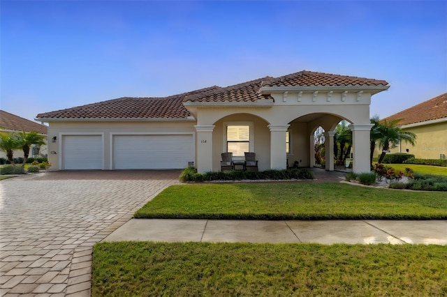 mediterranean / spanish-style house with a garage and a front lawn