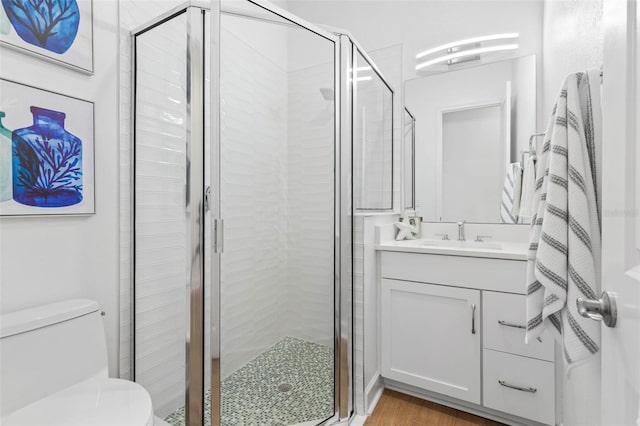 bathroom with hardwood / wood-style flooring, vanity, toilet, and a shower with shower door