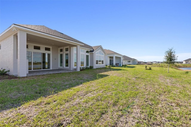 rear view of house featuring a lawn and a patio