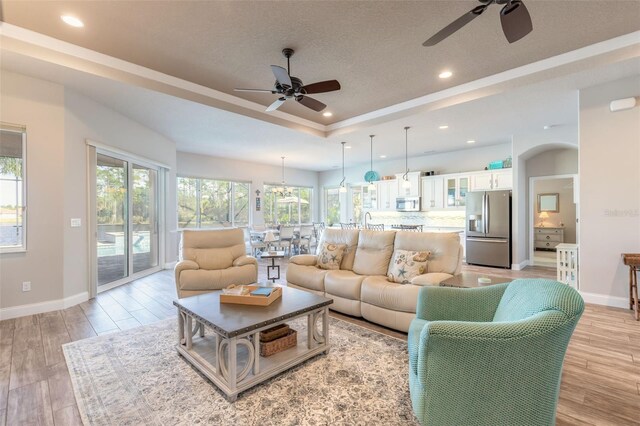 living room with a wealth of natural light, ceiling fan, and light hardwood / wood-style floors