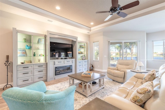 living room with a wealth of natural light, ceiling fan, light hardwood / wood-style floors, and ornamental molding