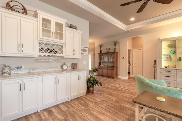 kitchen featuring light stone countertops, a raised ceiling, light hardwood / wood-style floors, and white cabinetry