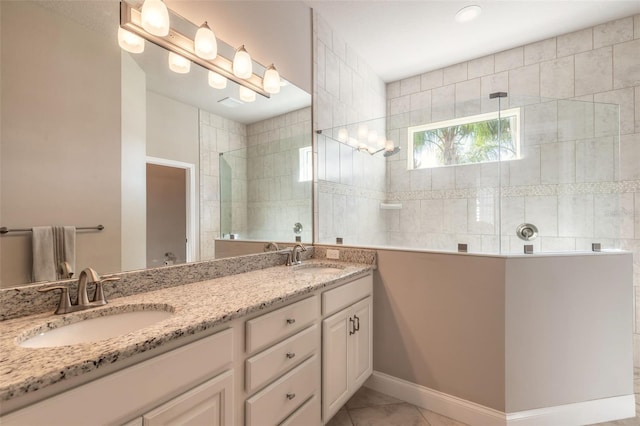 bathroom featuring tile patterned flooring, vanity, and tiled shower