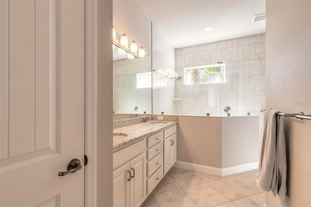 bathroom featuring a tile shower, vanity, and tile patterned floors