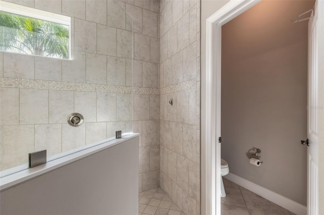 bathroom with a tile shower, tile patterned flooring, and toilet