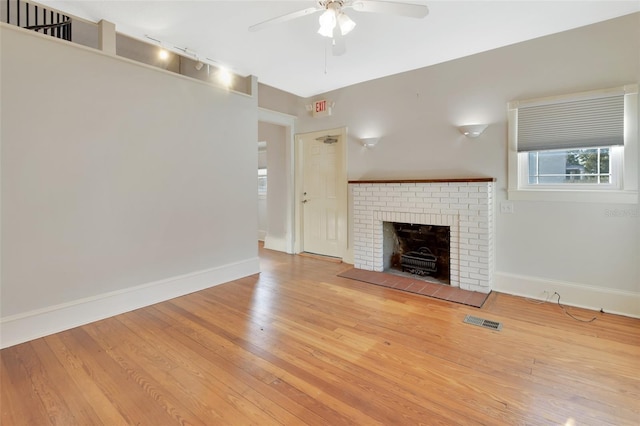 unfurnished living room featuring a fireplace, light wood-type flooring, and ceiling fan