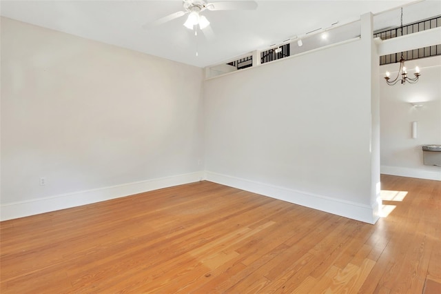 empty room with hardwood / wood-style floors and ceiling fan with notable chandelier