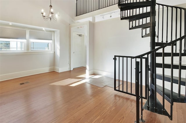 foyer featuring a towering ceiling, light hardwood / wood-style flooring, and a notable chandelier