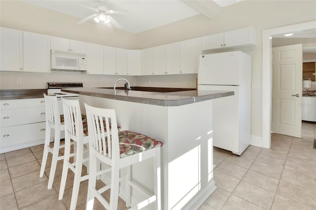 kitchen featuring light tile patterned floors, white appliances, white cabinetry, and a kitchen breakfast bar