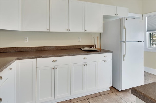 kitchen featuring white cabinets, white fridge, and light tile patterned floors