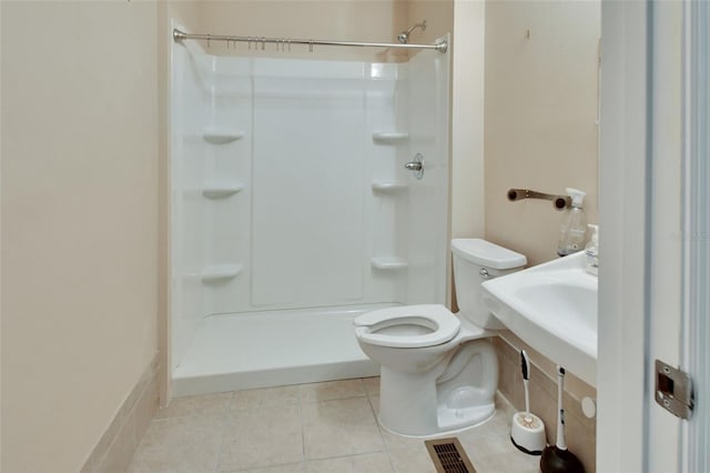 bathroom featuring a shower, tile patterned flooring, and toilet