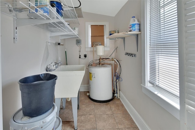 washroom with a healthy amount of sunlight, light tile patterned flooring, sink, and water heater