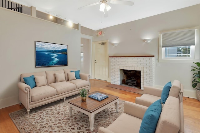 living room featuring ceiling fan, light hardwood / wood-style flooring, and a brick fireplace