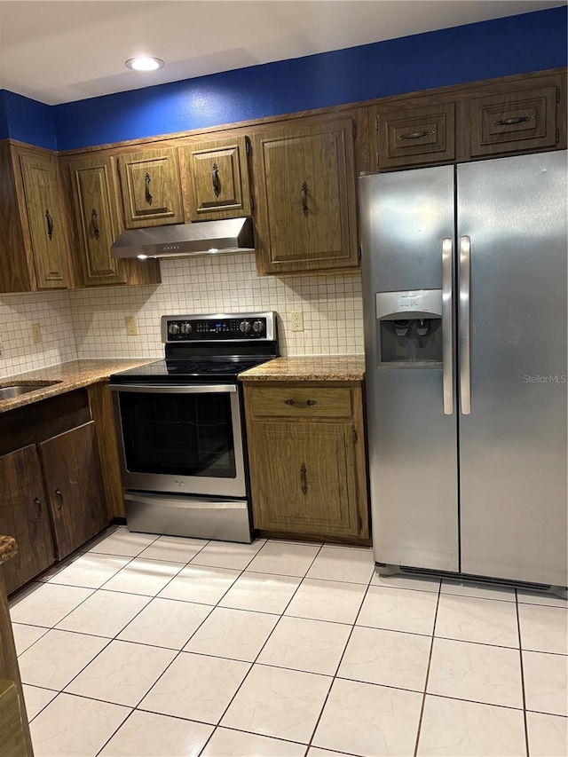 kitchen with backsplash, light stone countertops, light tile patterned floors, and stainless steel appliances