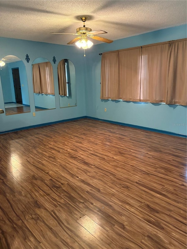 spare room featuring a textured ceiling, ceiling fan, and dark wood-type flooring