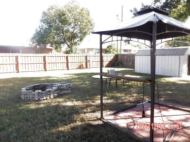 view of yard with a gazebo, a fire pit, and a storage shed