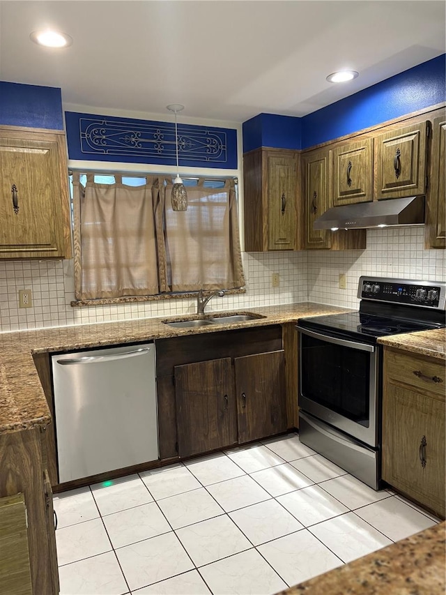 kitchen featuring sink, decorative backsplash, light stone countertops, appliances with stainless steel finishes, and light tile patterned flooring