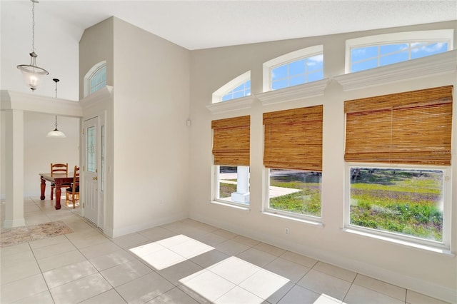 empty room with a wealth of natural light, light tile patterned floors, and high vaulted ceiling