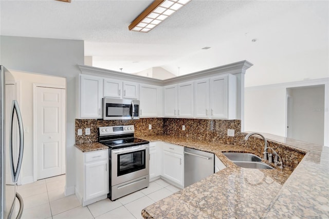 kitchen with stainless steel appliances, vaulted ceiling, white cabinetry, and sink