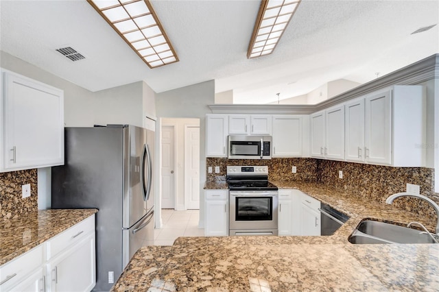 kitchen with white cabinets, sink, vaulted ceiling, decorative backsplash, and appliances with stainless steel finishes