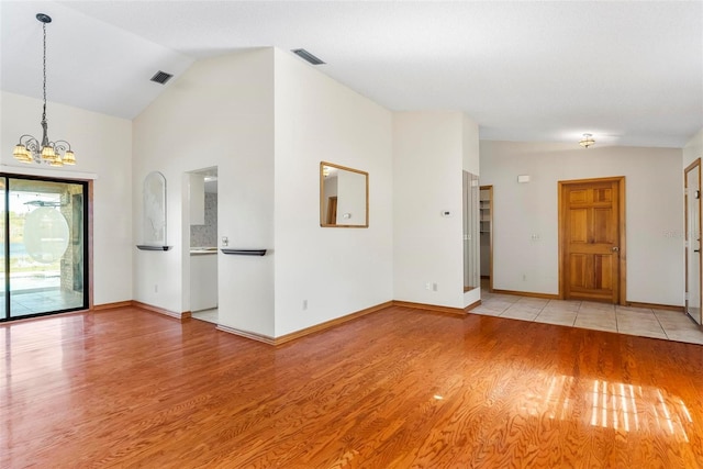 interior space with light wood-type flooring, lofted ceiling, and a notable chandelier